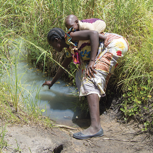 A woman in Malawi gathers water from a polluted water source that serves 1,100 people.
