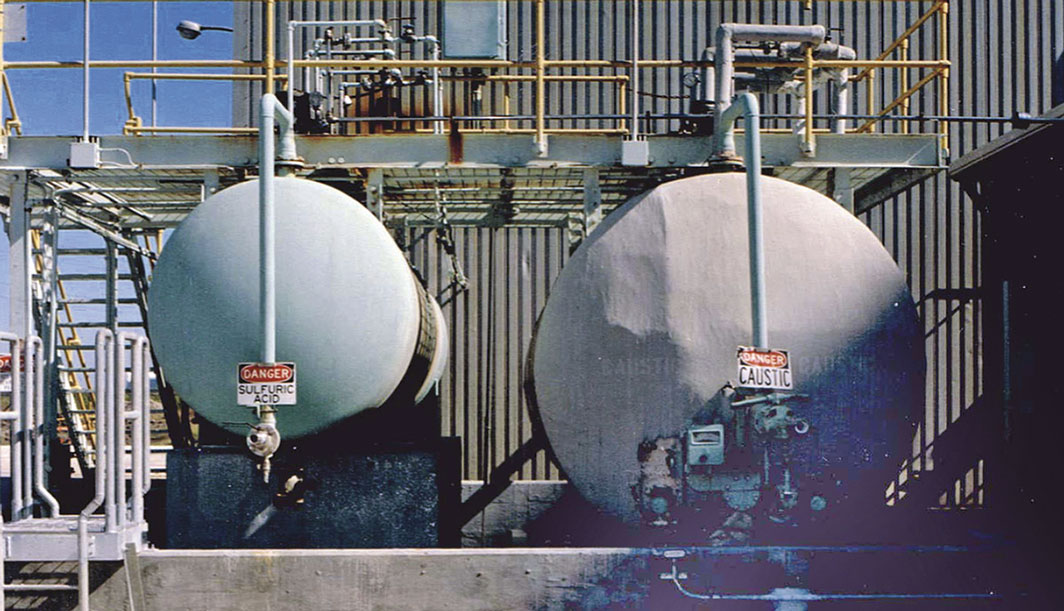 Image 2. The sulfuric acid and sodium hydroxide needed for the ion exchange purification process is stored in these large tanks outside the processing building.
