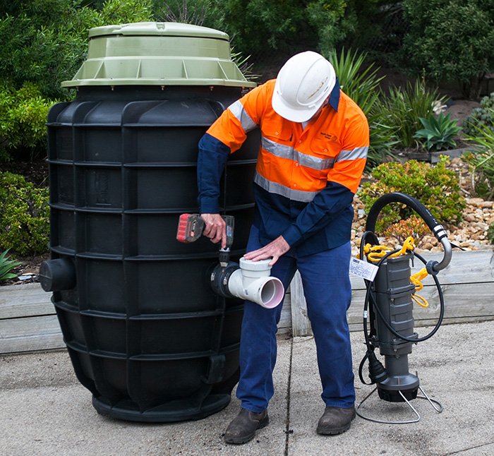 A contractor attaches the inlet fitting to the tank prior to in-ground installation.