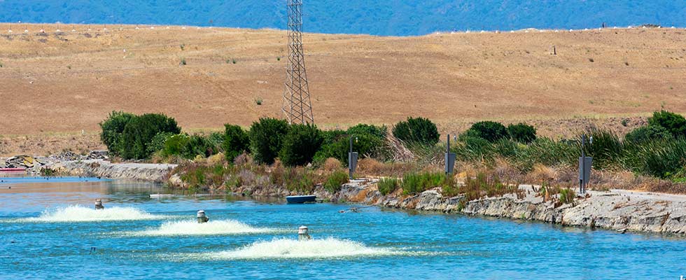 Three electric motor-driven aerators working to oxygenate water in a treatment pond