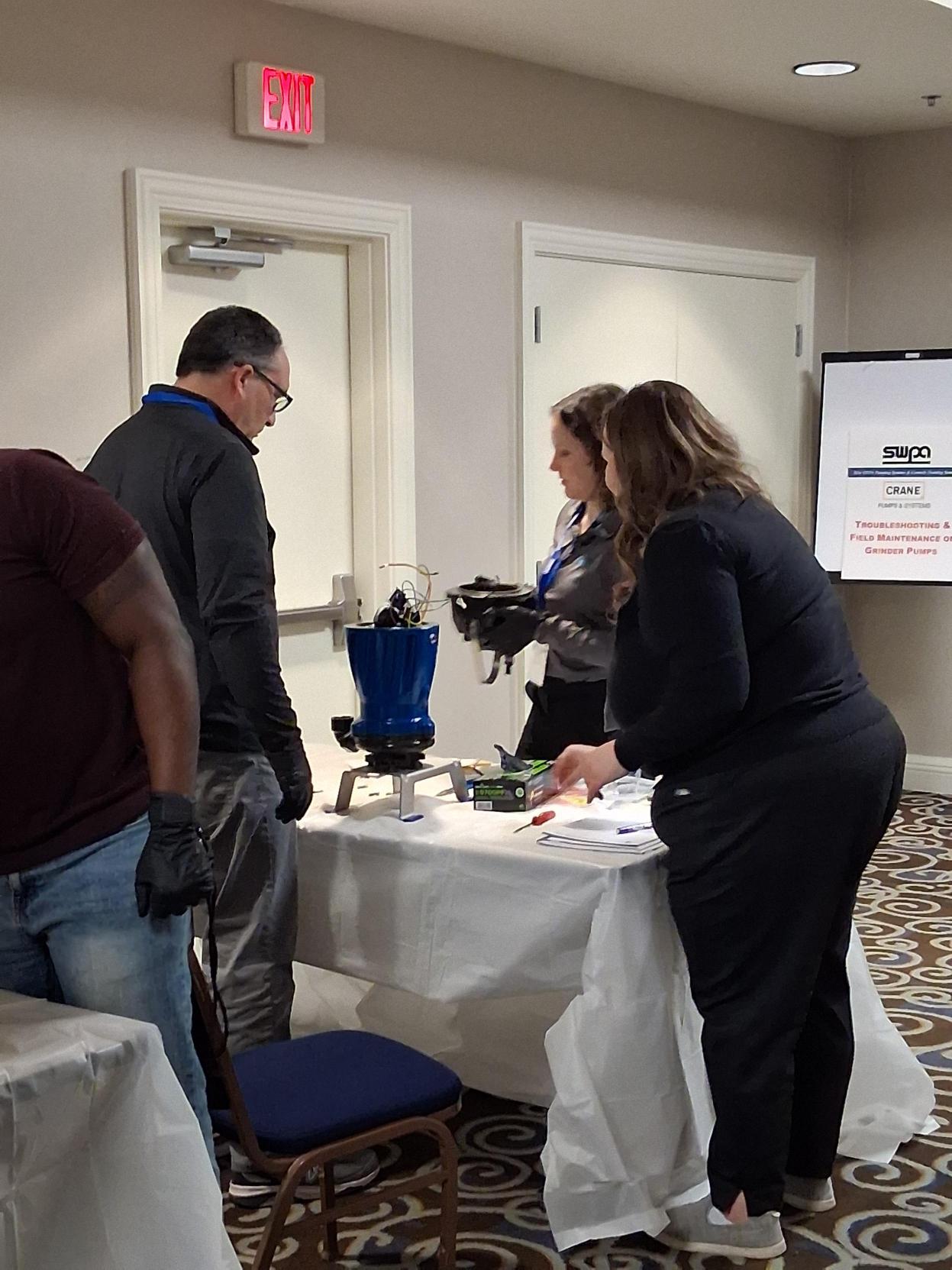 Image 3: Seminar attendees work at disassembling a pump