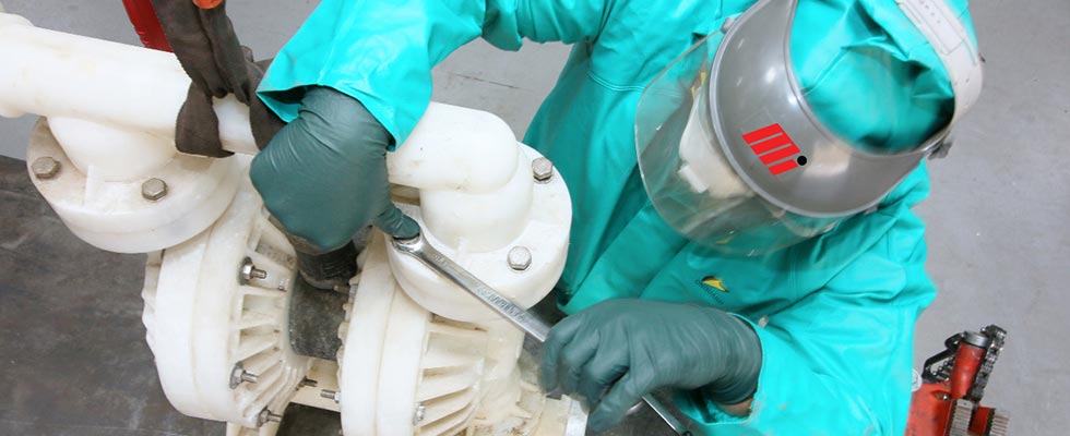 Worker in PPE disassembling an air-operated double-diaphragm (AODD) that is pumping hydrochloric acid.