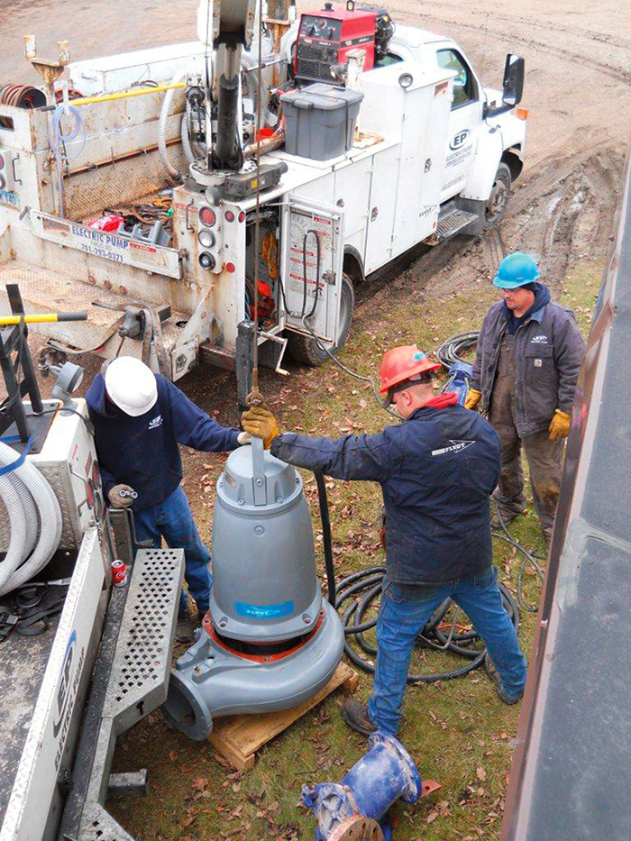 A three-man crew uncrates and prepares the new pump for installation after piping modifications.