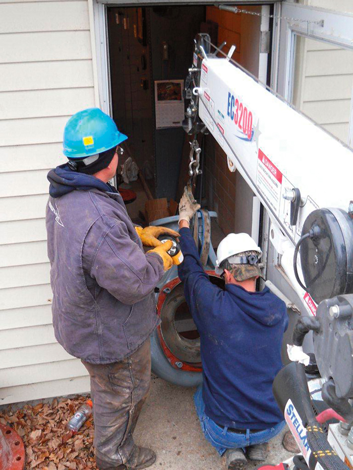 The crew maneuvers and lowers the volute for the replacement pump through the side door into the station.