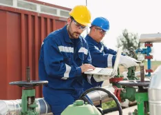 Two engineers working inside oil and gas refinery