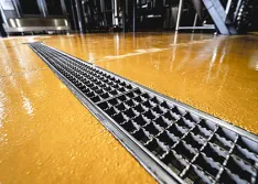 Brewery production floor clean-in-place (CIP) process: High-temperature fluids and debris are directed through grates for efficient removal.