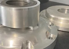IMAGE 1: A custom housing designed for a bushing that retains the upper bearing (front)  and an OEM upper bearing retainer that utilizes aluminum as a bushing material (back). (Image courtesy of Niche Cryogenic Services) 